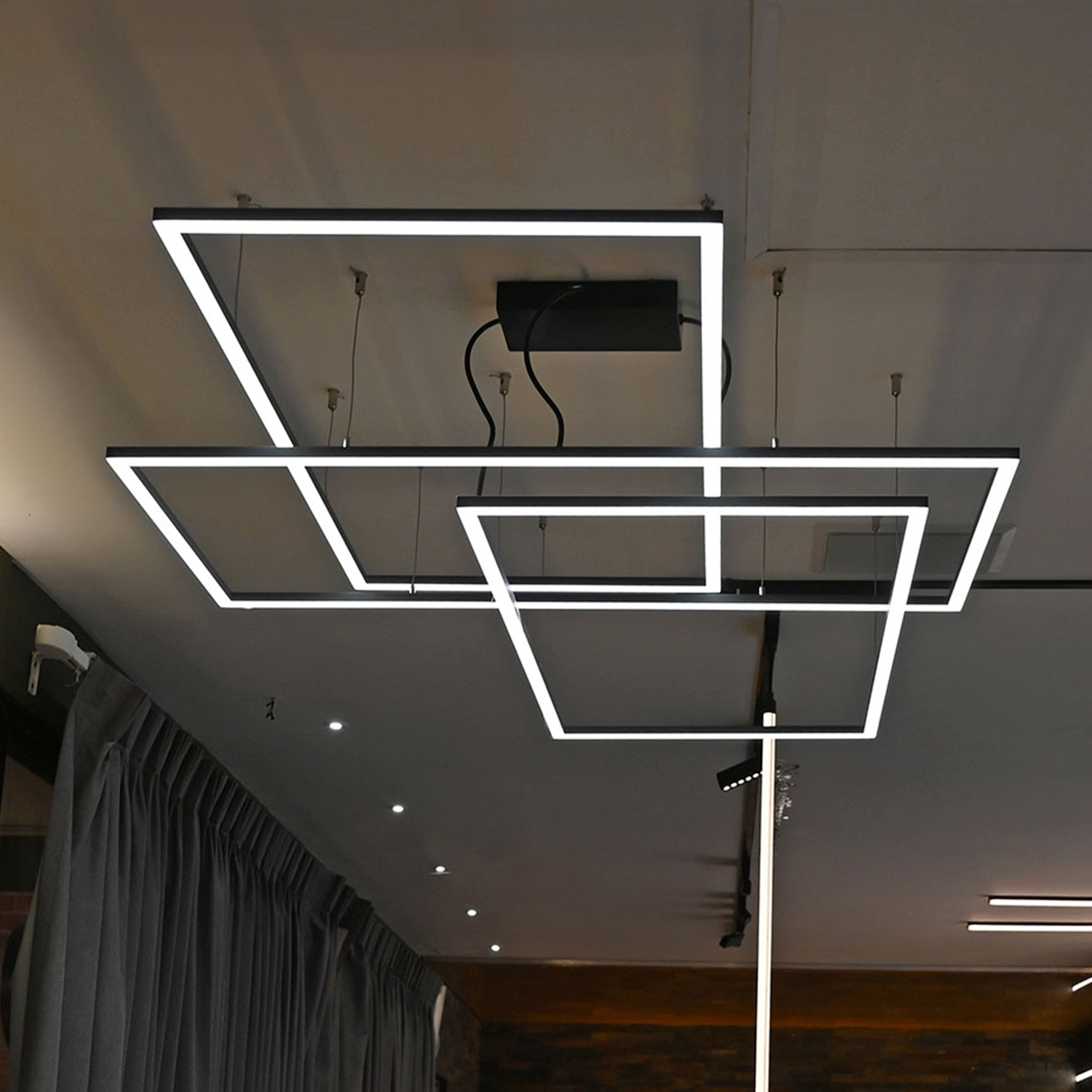 Luminarios suspendidos con tres rectángulos de iluminación en color negro rugoso con iluminación blanco neutro