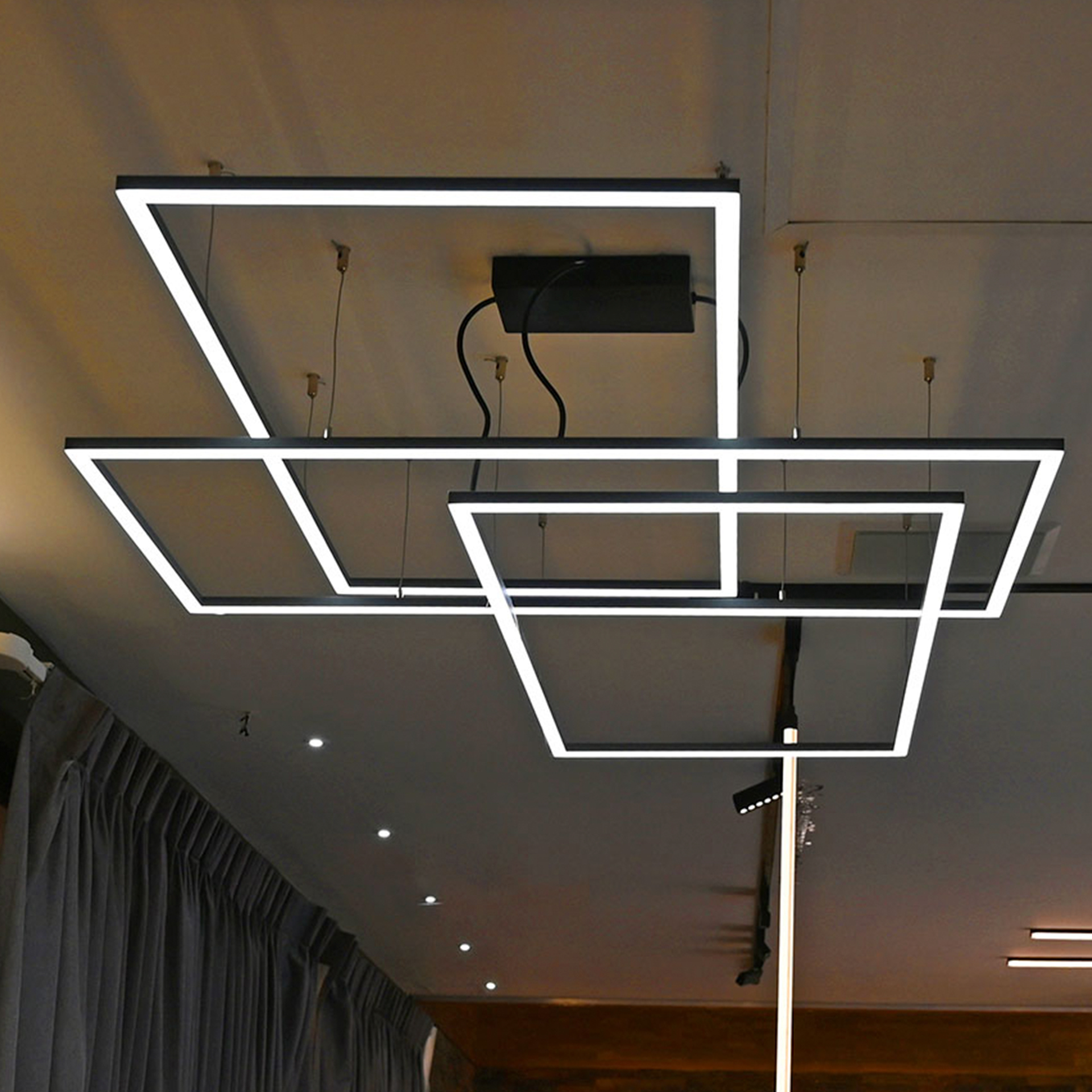 Luminarios suspendidos con tres rectángulos de iluminación en color negro con iluminación blanco cálido