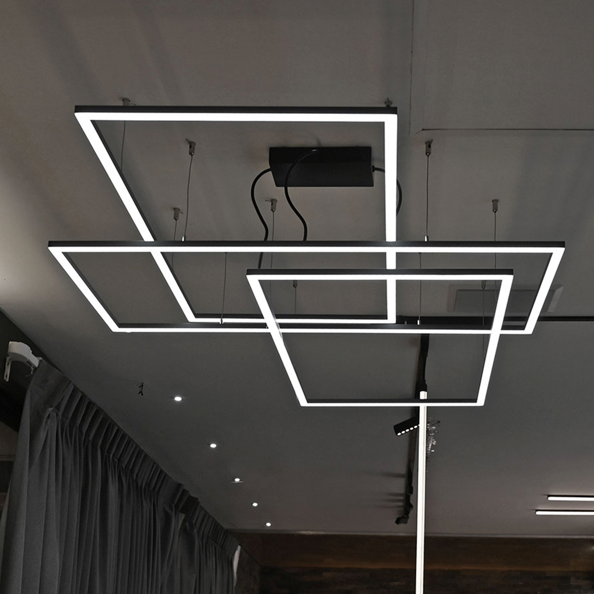Luminarios suspendidos con tres rectángulos de iluminación en color negro brillante con iluminación luz de día