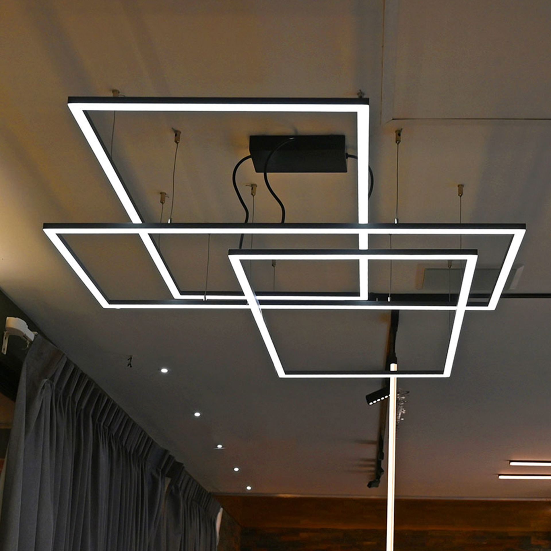 Luminarios suspendidos con tres rectángulos de iluminación en color negro brillante con iluminación blanco cálido