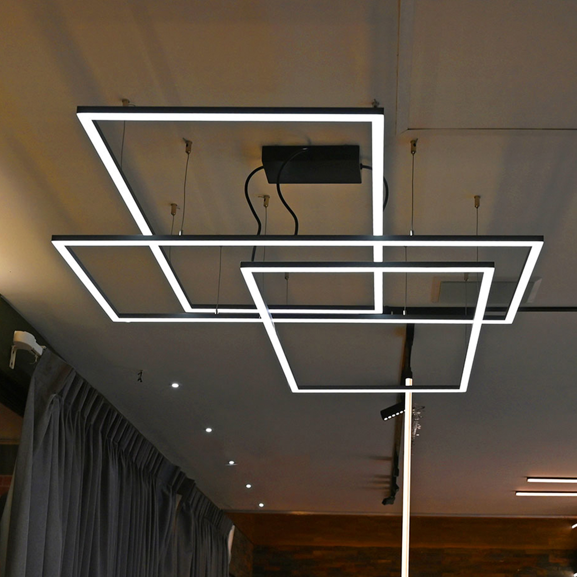 Luminarios suspendidos con tres rectángulos de iluminación en color blanco mate con iluminación blanco cálido