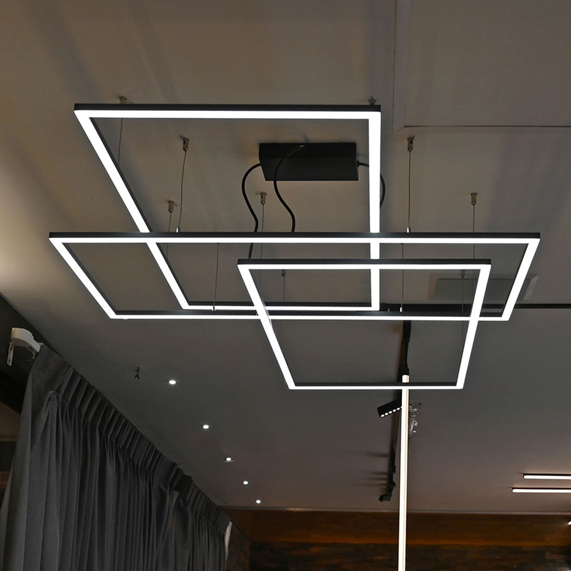 Luminarios suspendidos con tres rectángulos de iluminación en color champagne con iluminación blanco neutro