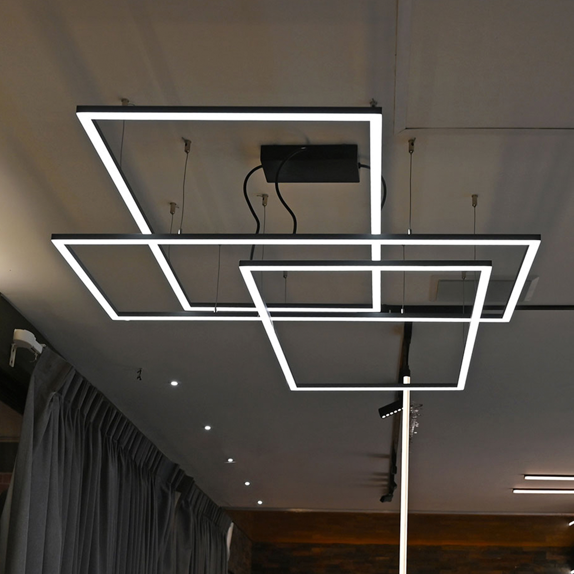 Luminarios suspendidos con tres rectángulos de iluminación en color gris con iluminación blanco neutro